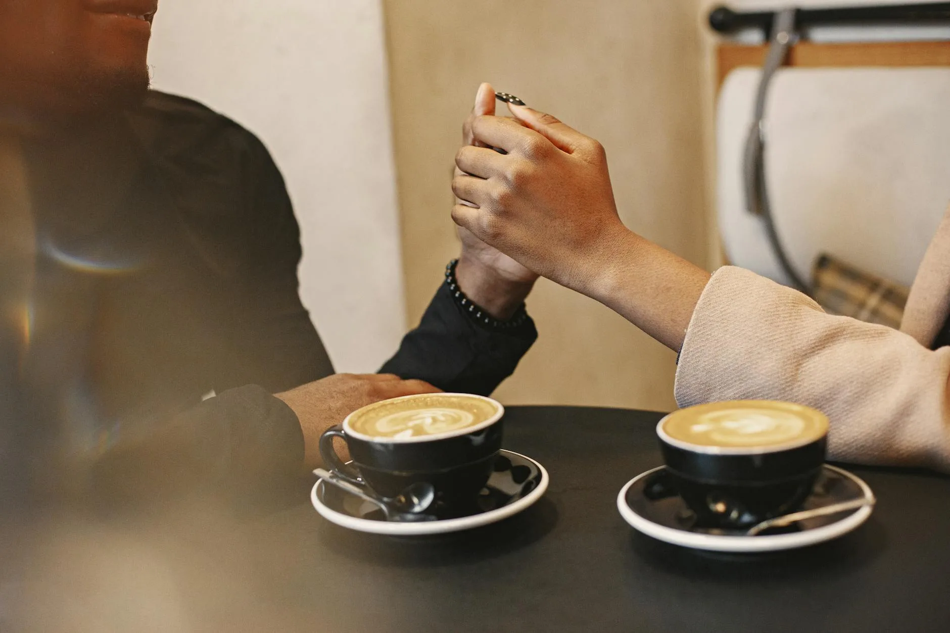 Couple holding hands over coffee — the meaningful connection professional matchmakers help career-focused singles find